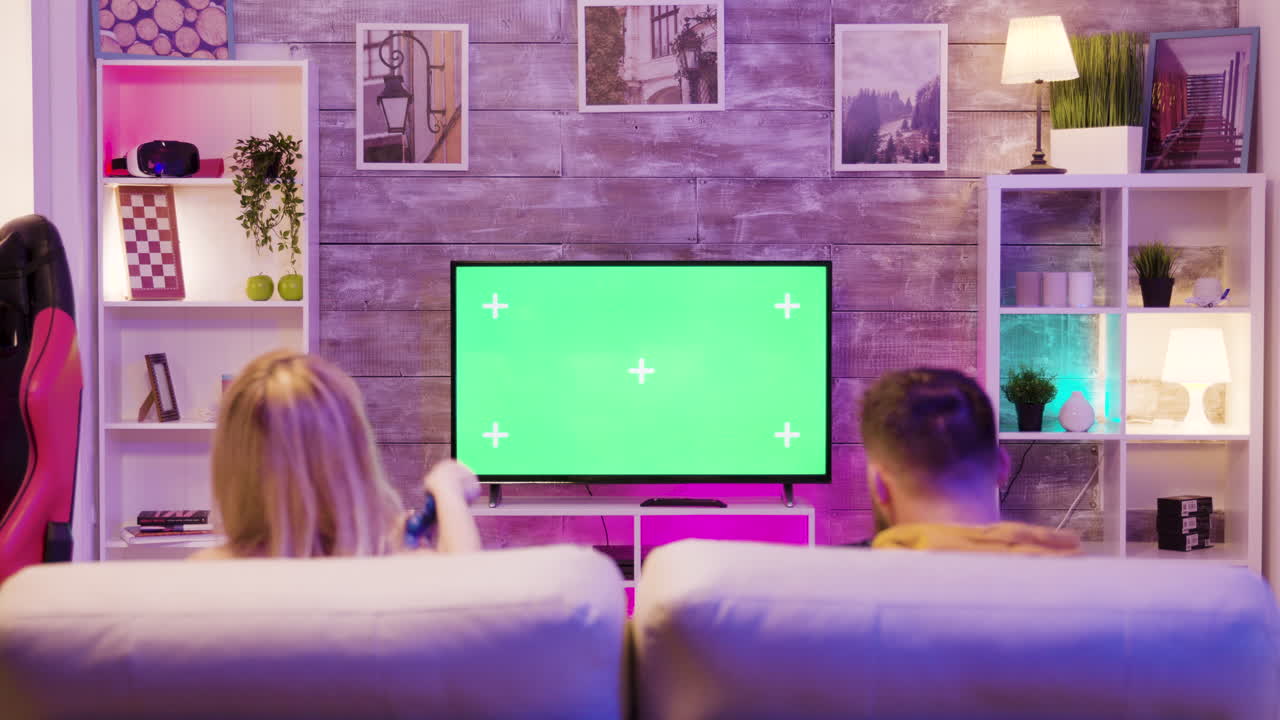 Couple playing video games on TV with green screen in living room