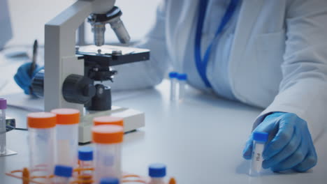 primer plano de un trabajador de laboratorio que realiza investigaciones utilizando un microscopio con un tubo de ensayo etiquetado psi
