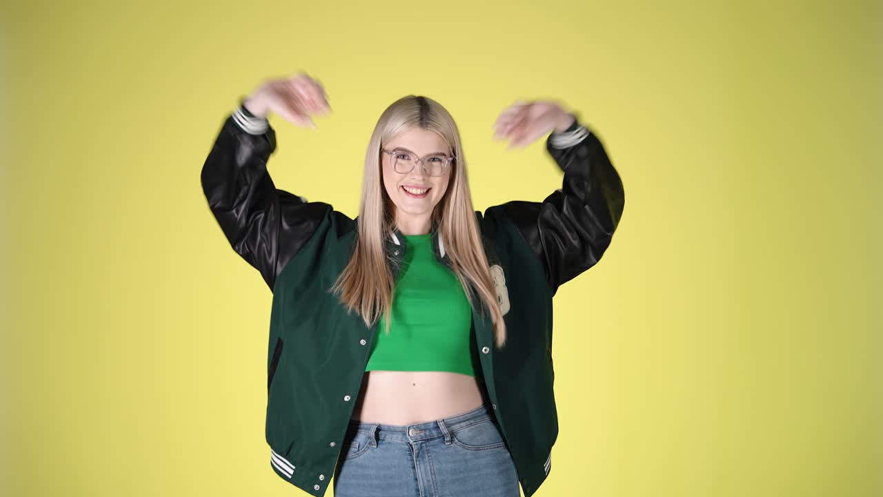 Joyful Young Blonde Woman Smiling Dancing With Arms Raised, Studio Portrait