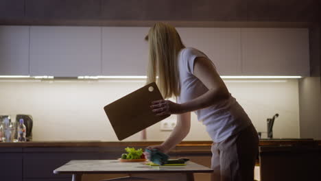 Blonde-woman-cleans-table-with-rug-before-cooking-dinner