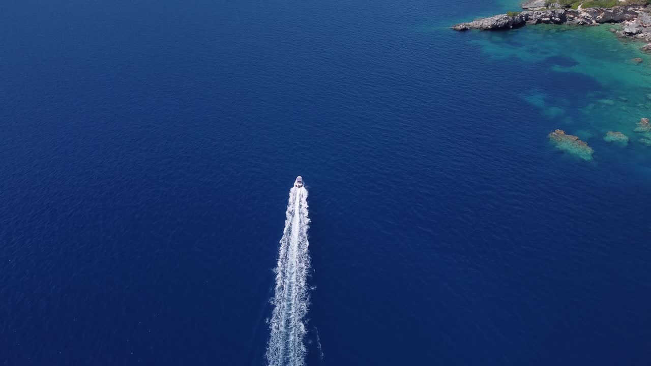 Aerea: motoscafo che sfreccia sull'acqua azzurra del mare vicino a un'isola a Lefkada, Grecia - ripresa in tracking con drone.