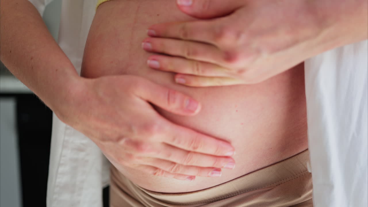 Close up of a woman rubbing her pregnant belly with oil