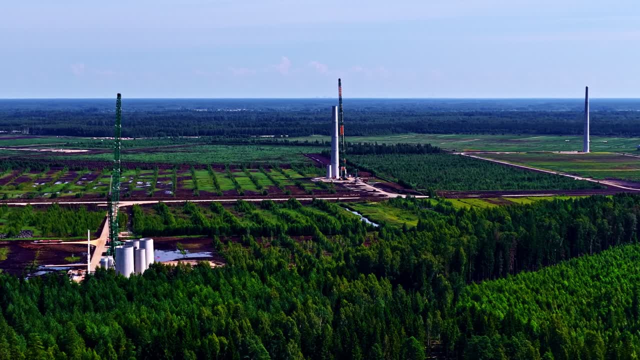 Wind turbine towers being built in a large rural and forested area. Aerial drone panoramic view, copy space