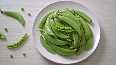 fresh sweet green peas on white plate