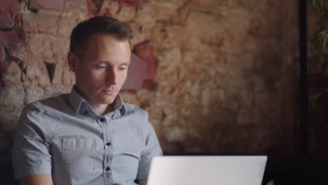 a serious man is a business student working studying sitting at a table and typing a message on a laptop. typing text on the keyboard