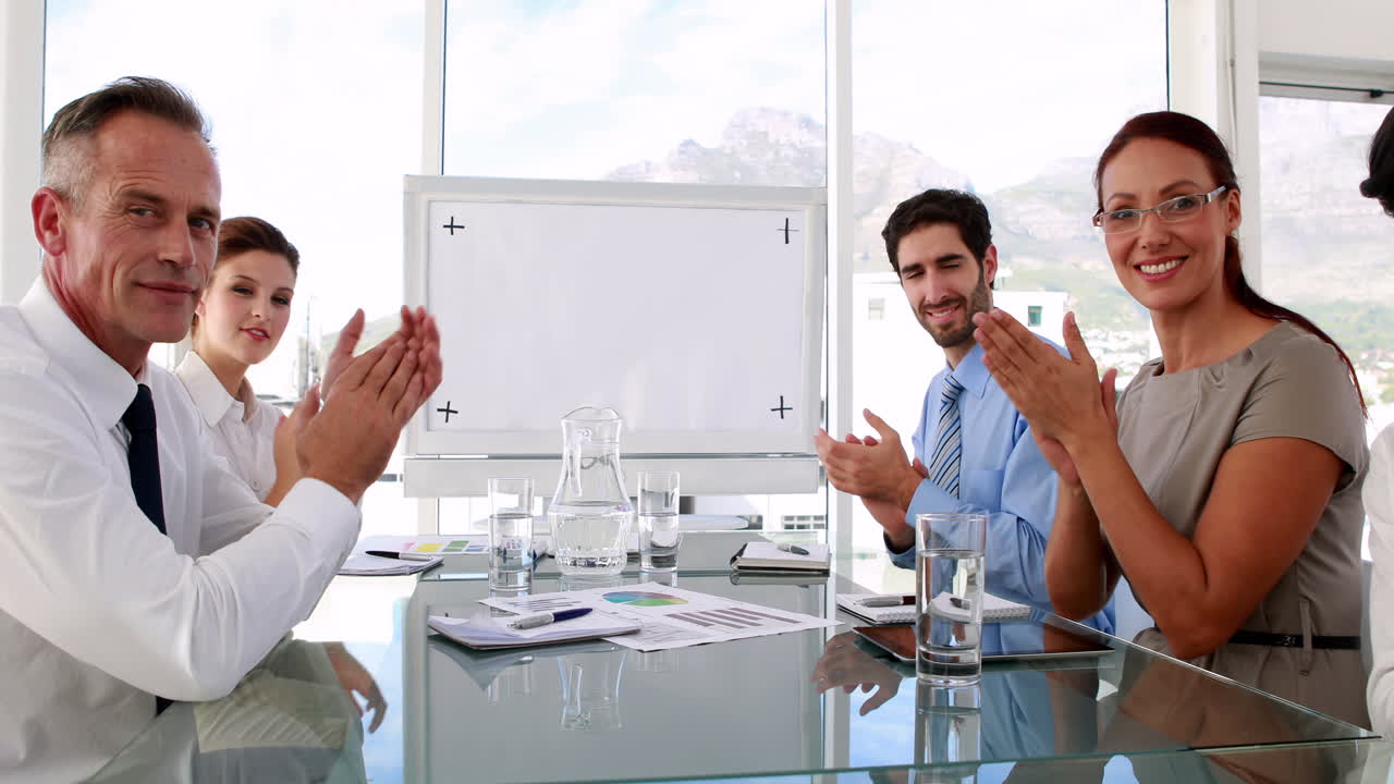Business team applauding the camera at meeting
