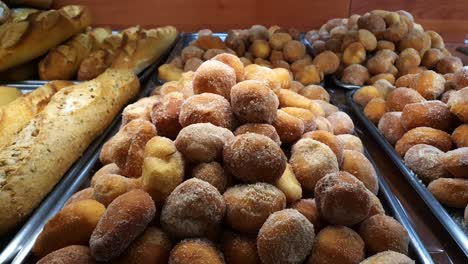 brazilian donuts sprinkled with sugar being displayed at a brazilian bakery showcase.