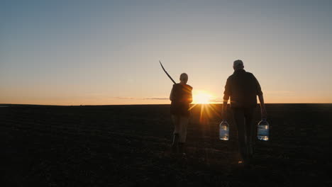 farmers walking in a field at sunset