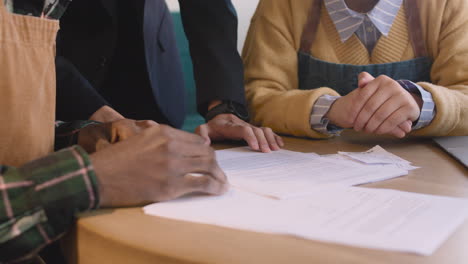 three unrecognizable small business owners doing accounting in their coffee shop