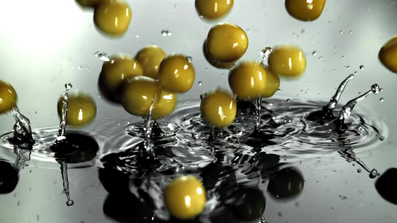Olive verdi che cadono e schizzano nell'acqua al rallentatore.