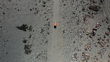 dramatic downward angle drone shot of a tuk tuk driving on a small gravel path in the gojal valley upper hunza of the gilgit baltistan, pakistan