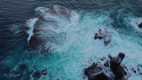 Birds-eye-drone-shot-over-tropical-crashing-waves-at-dusk