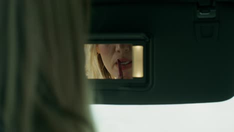 woman applying lipstick in car