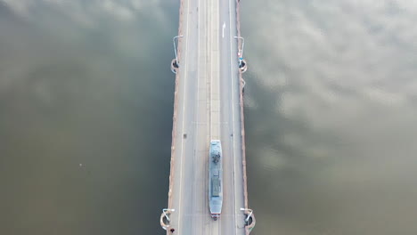 birdseye aerial view of tram moving on river bridge with sky mirror reflection