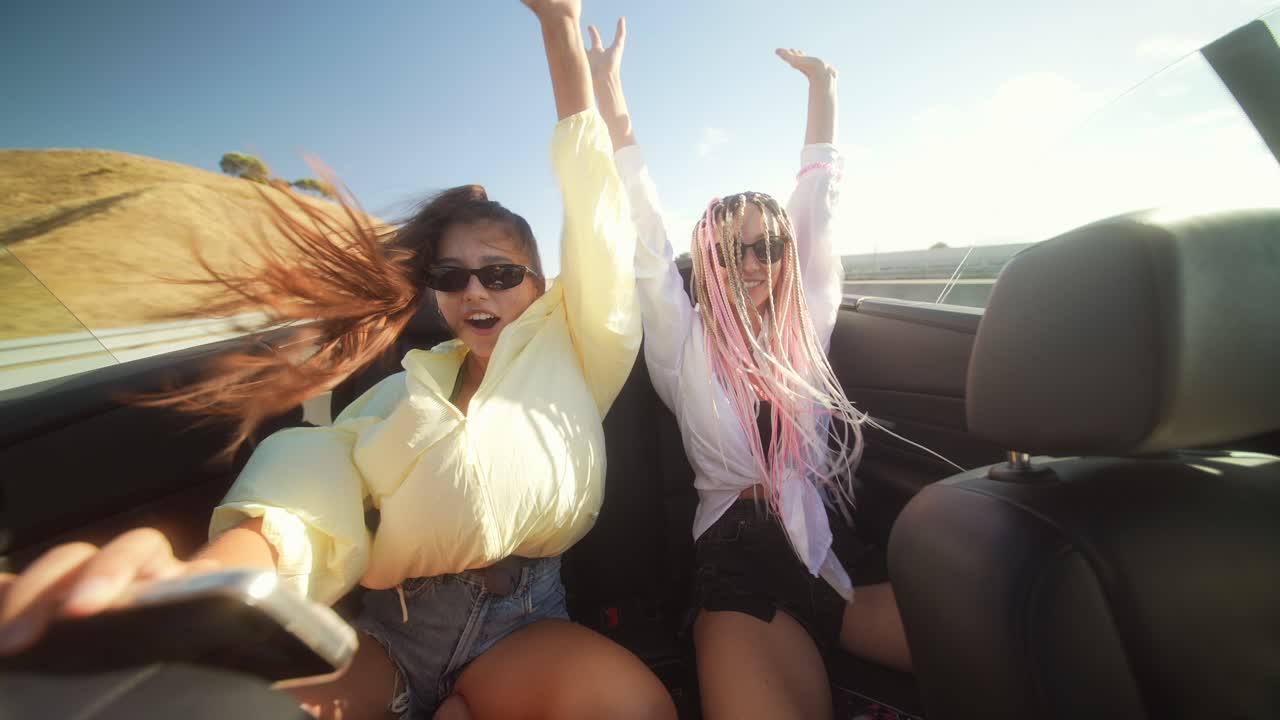 Two happy women enjoying a convertible road trip on a sunny day