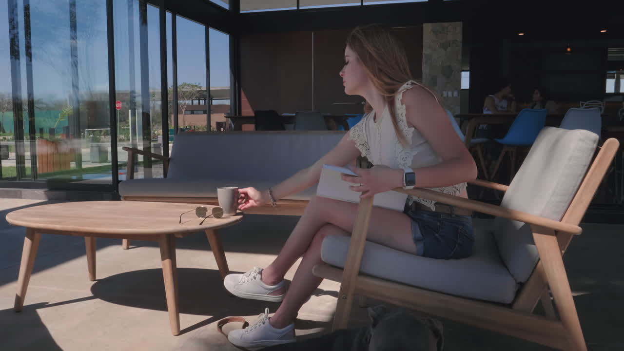 mujer joven tomando café y leyendo con su perro al aire libre a cámara lenta