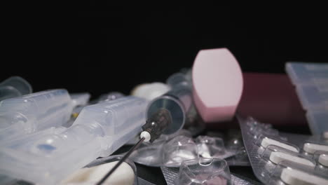 syringe and plastic ampules lie on different drugs on black