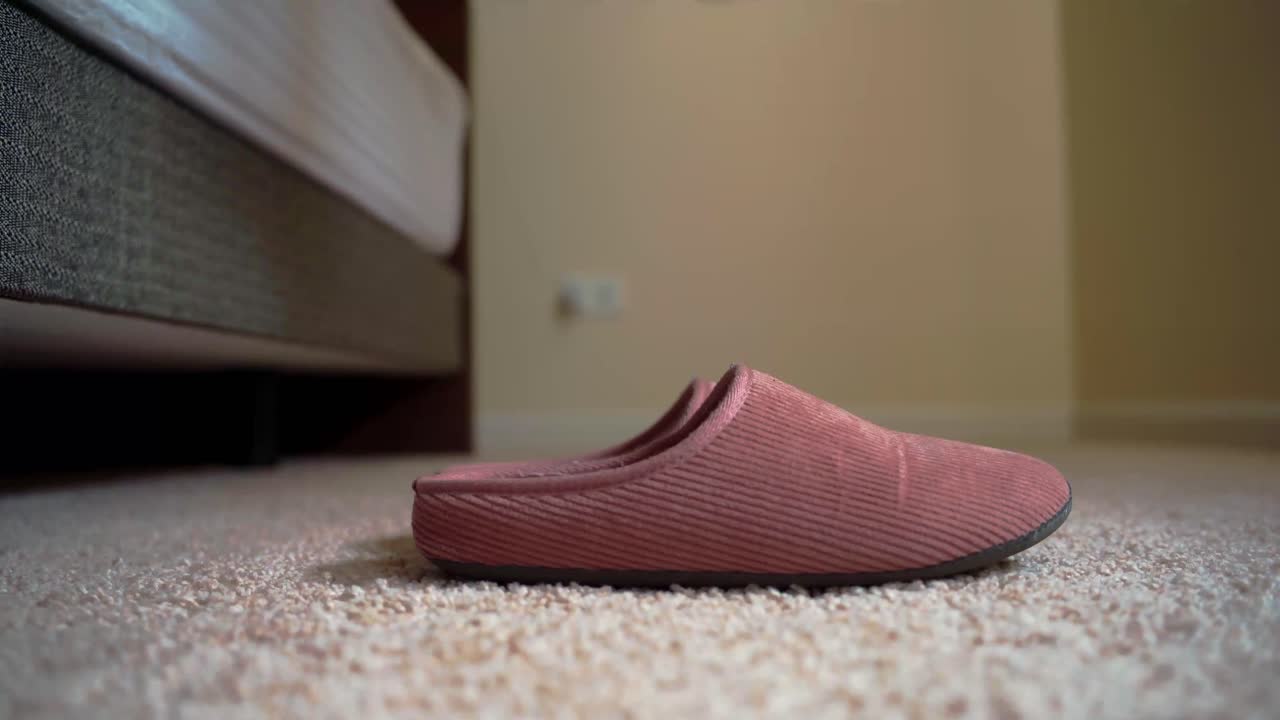 Close-up van de voet van een vrouw met een pantoffel aan op tapijt in de ochtend.