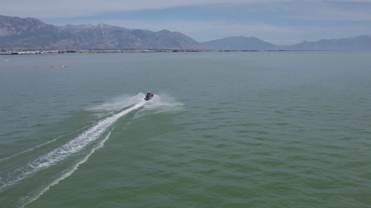 Jeździec na skuterze wodnym Sea Doo na jeziorze z pięknym górskim tłem, ujęcie z lotu ptaka.