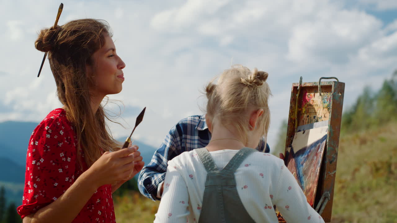 familia feliz creando imágenes al aire libre. madre pintando enseñando a los niños en la montaña