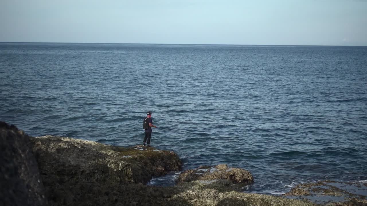 Fisherman fishing off the rocks on seaside