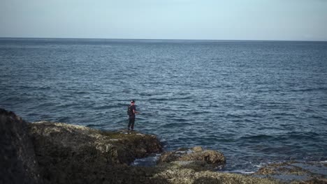 Fisherman fishing off the rocks on seaside