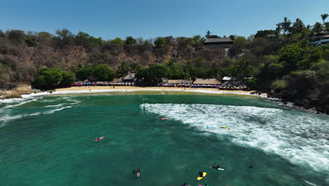 Drone-shot-over-SUP-boarders-at-the-Playa-Carrizalillo-beach-in-sunny-Puerto-Escondido,-Mexico