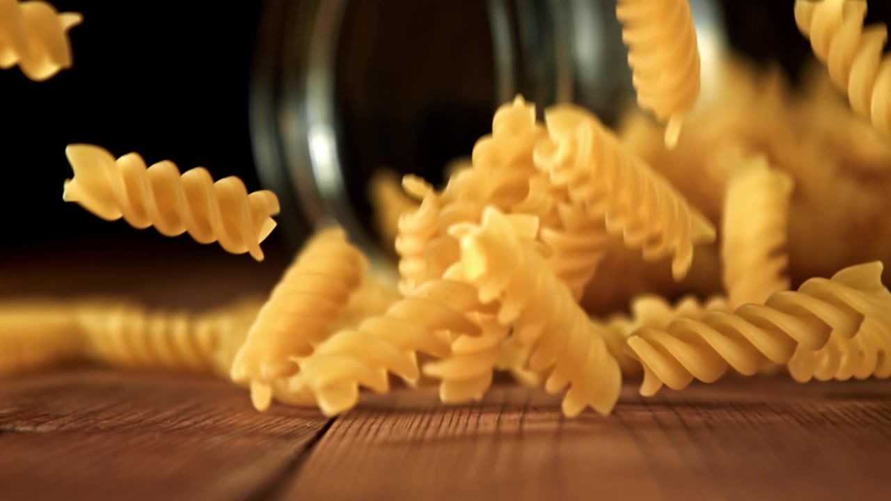 Slow Motion of Fusilli Pasta Falling onto a Wooden Table