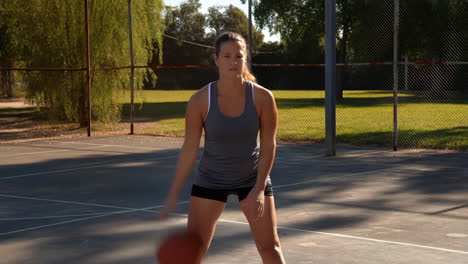 a woman dribbling a basketball on an outdoor court