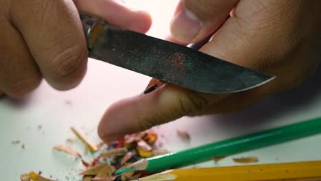 Footage-of-hands-slowly-sharpening-a-pencil-and-some-coloured-pencils-with-a-sharp-knife