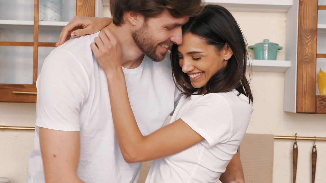 um casal feliz a abraçar-se na cozinha.