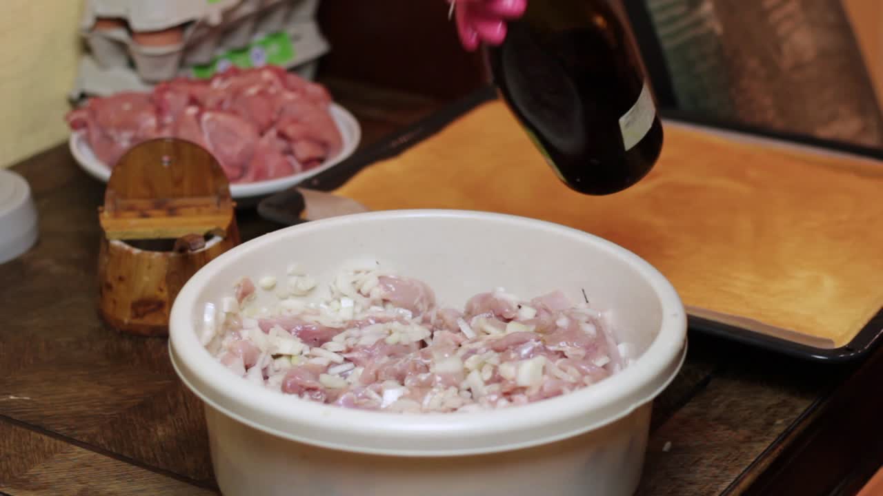 가정 주방장이 장갑을 낀 손으로 섞기 전에 식초를 고기에 붓고 양념합니다