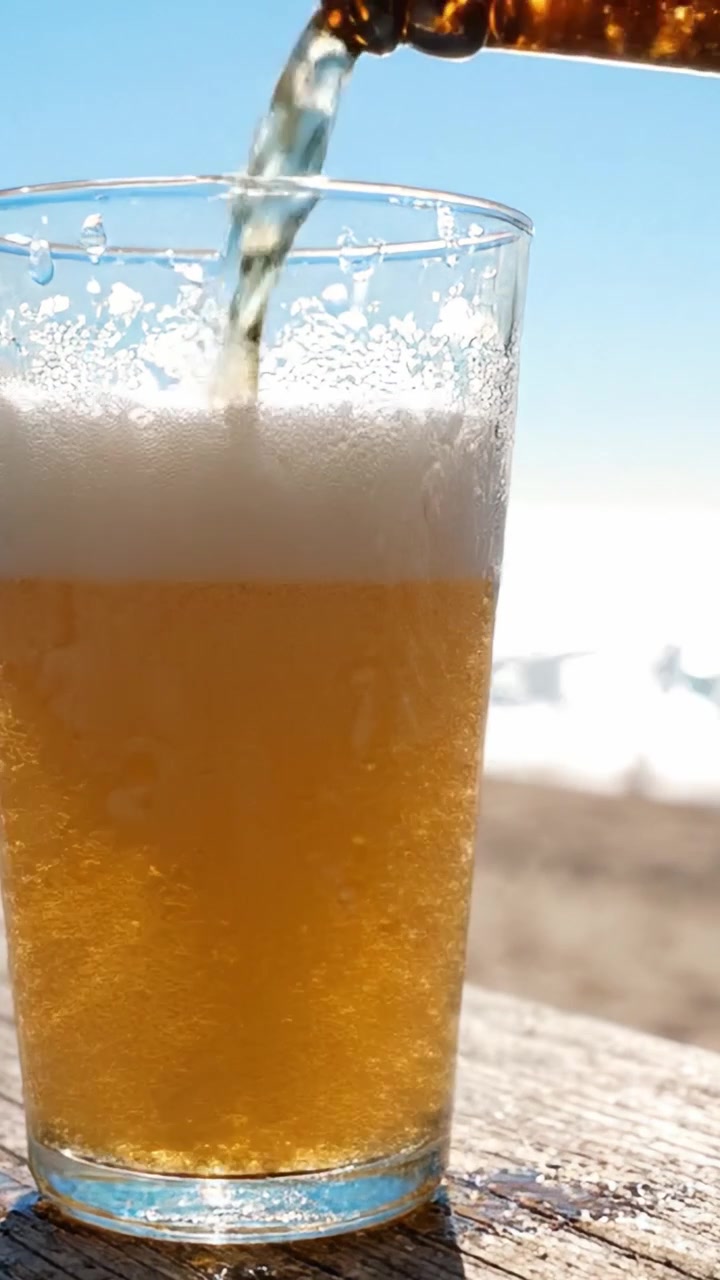 Un bicchiere di birra rinfrescante che brilla sotto il sole con un bellissimo sfondo all'aperto, catturando l'essenza di una perfetta giornata estiva
