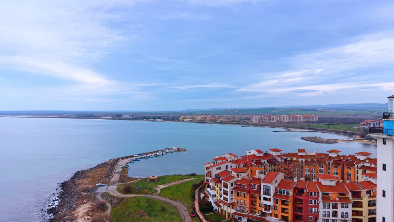 Baia costiera con un piccolo molo ed edifici residenziali. Vista aerea di una baia marina, un molo in pietra con barche ed edifici moderni sulla riva.
