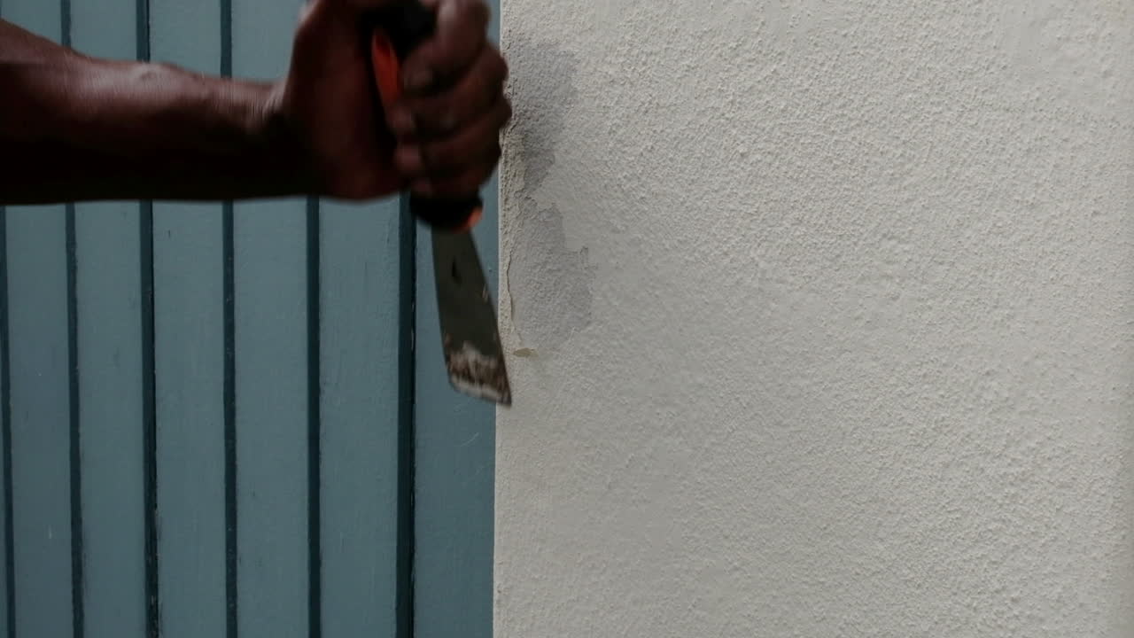 imágenes de primer plano de la mano de un hombre africano negro preparando una pared externa para pintar