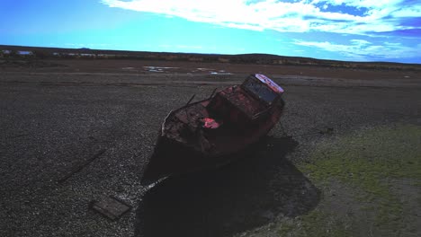 circular drone view of a wrecked ship rusted on beach at bahia bustamante with deep blue sky and clouds