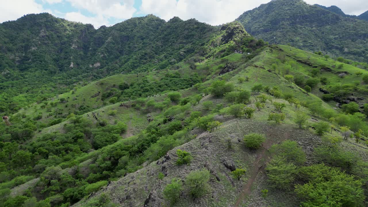 Drone che vola lungo l'inizio di una cresta montuosa coperta da vegetazione verde