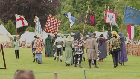 knights parade walking with their squires and their banners, celebrating their victory at the queen's joust in leeds castle, kent, england