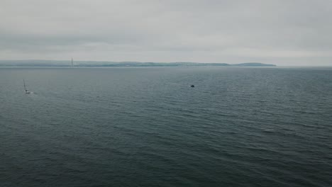 Reversing-and-ascending-wide-aerial-reveal-shot-of-vast-sea-and-boats