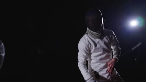 two fencers in action during a night competition