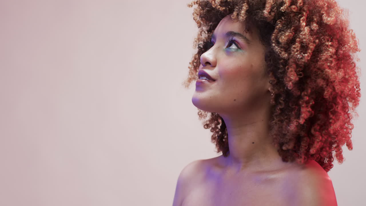 mujer biracial con cabello oscuro en luz azul y rosa con espacio de copia, cámara lenta