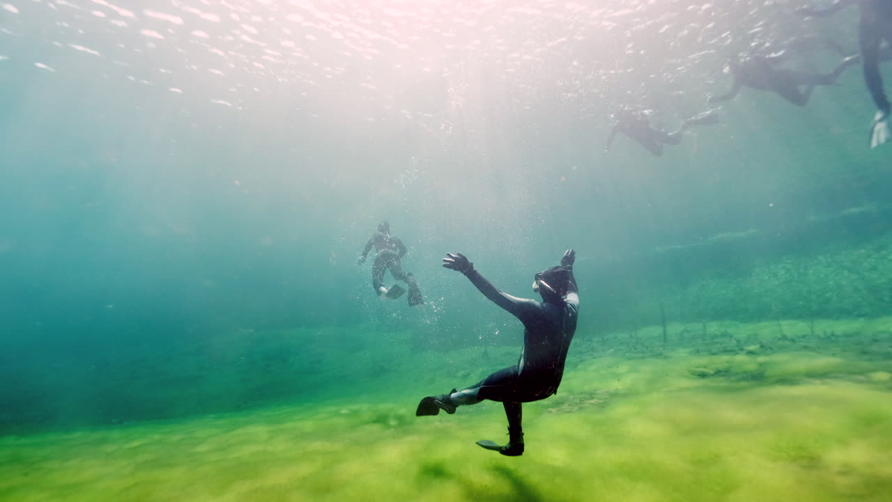 Beautiful underwater shot showing silhouette of divers in freshwater pond named Ewens in National Park.Sunny day with lighting plants underwater.