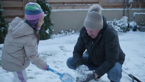 grandfather and granddaughter having fun in the snow