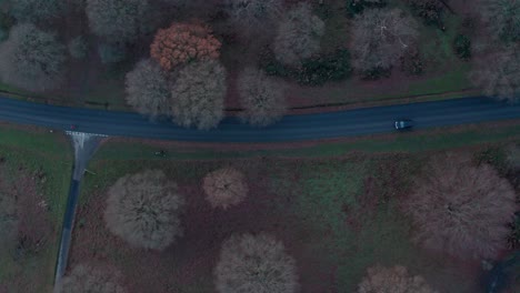 Aerial-top-down-drone-shot-of-cars-and-bicycles-on-main-road-in-richmond-park-London