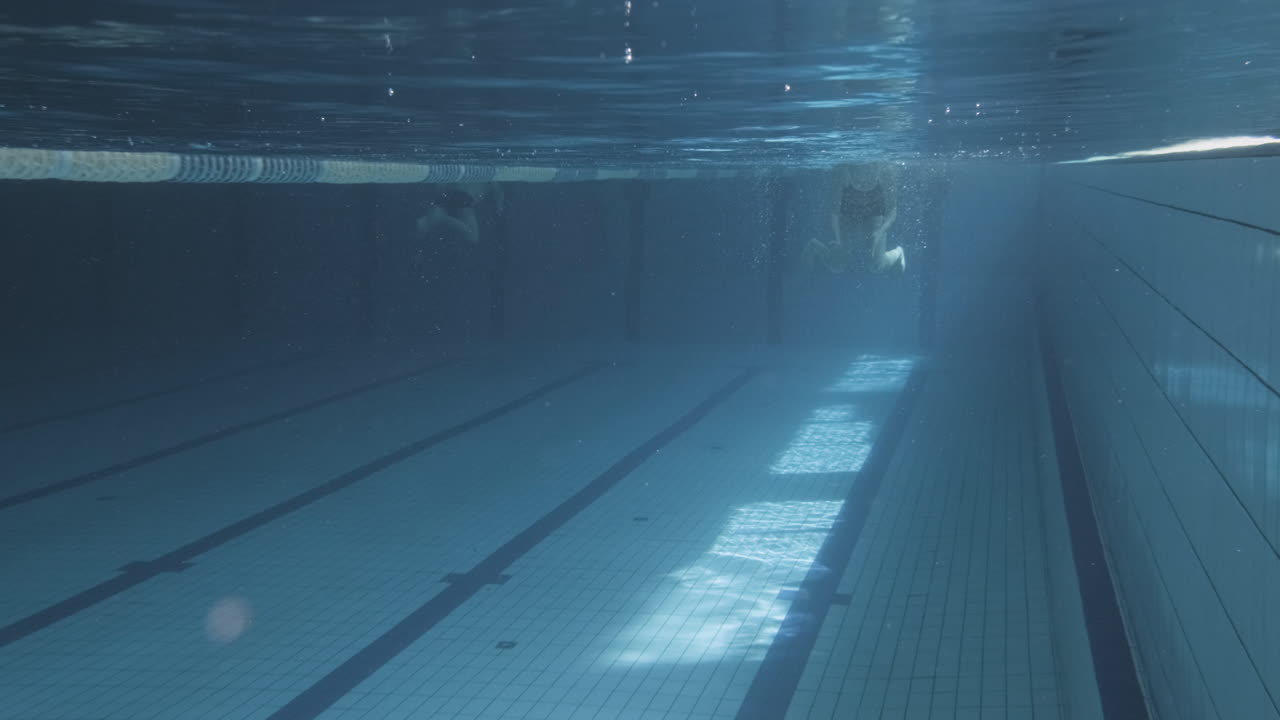 подводный снимок молодой женщины, плавающей брассом в закрытом бассейне
