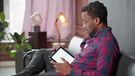 man using a tablet on a couch