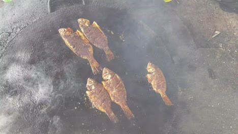 spicy fish being fried in a big cast iron pan