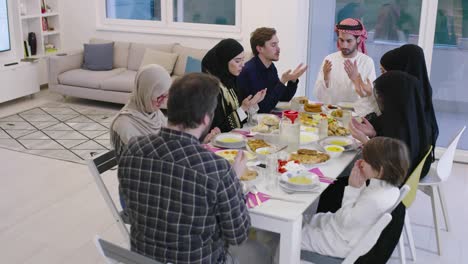 eid mubarak muslim people praying before iftar dinner. eating traditional food during ramadan feasting month at home.