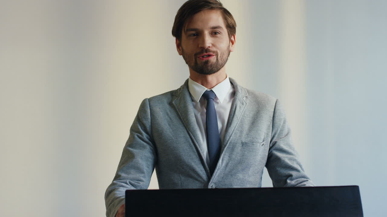 정장을 입고 회의실에서 많은 사람들 앞에서 이야기하는 연단에 있는 백인 사업가 연사의 클로즈업 보기