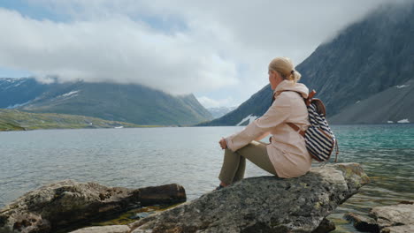 a woman looks at a high-altitude lake in norway seclusion and run away from the whole concept 4k vid